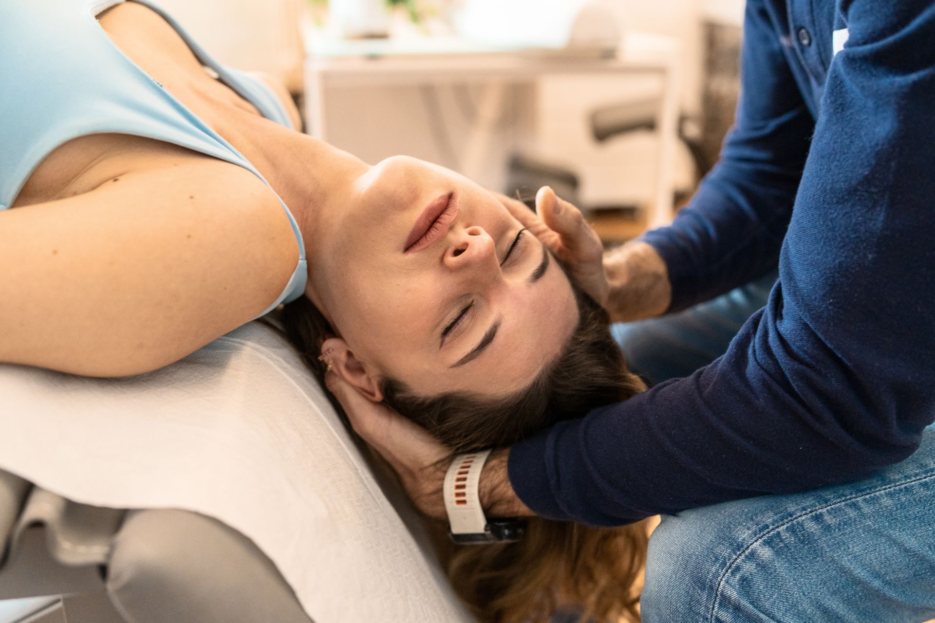 A woman is laying on a table getting a neck massage from a man.