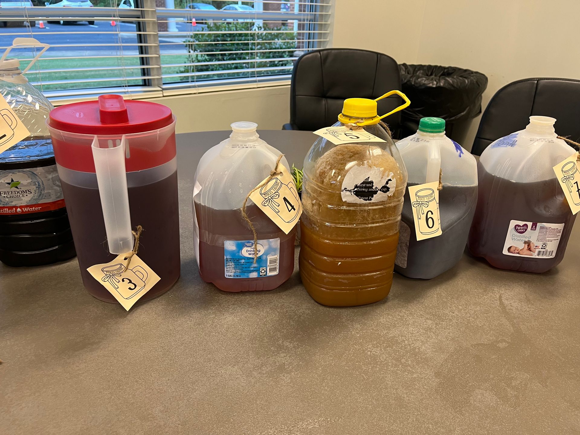 Several gallons of liquid are lined up on a table.