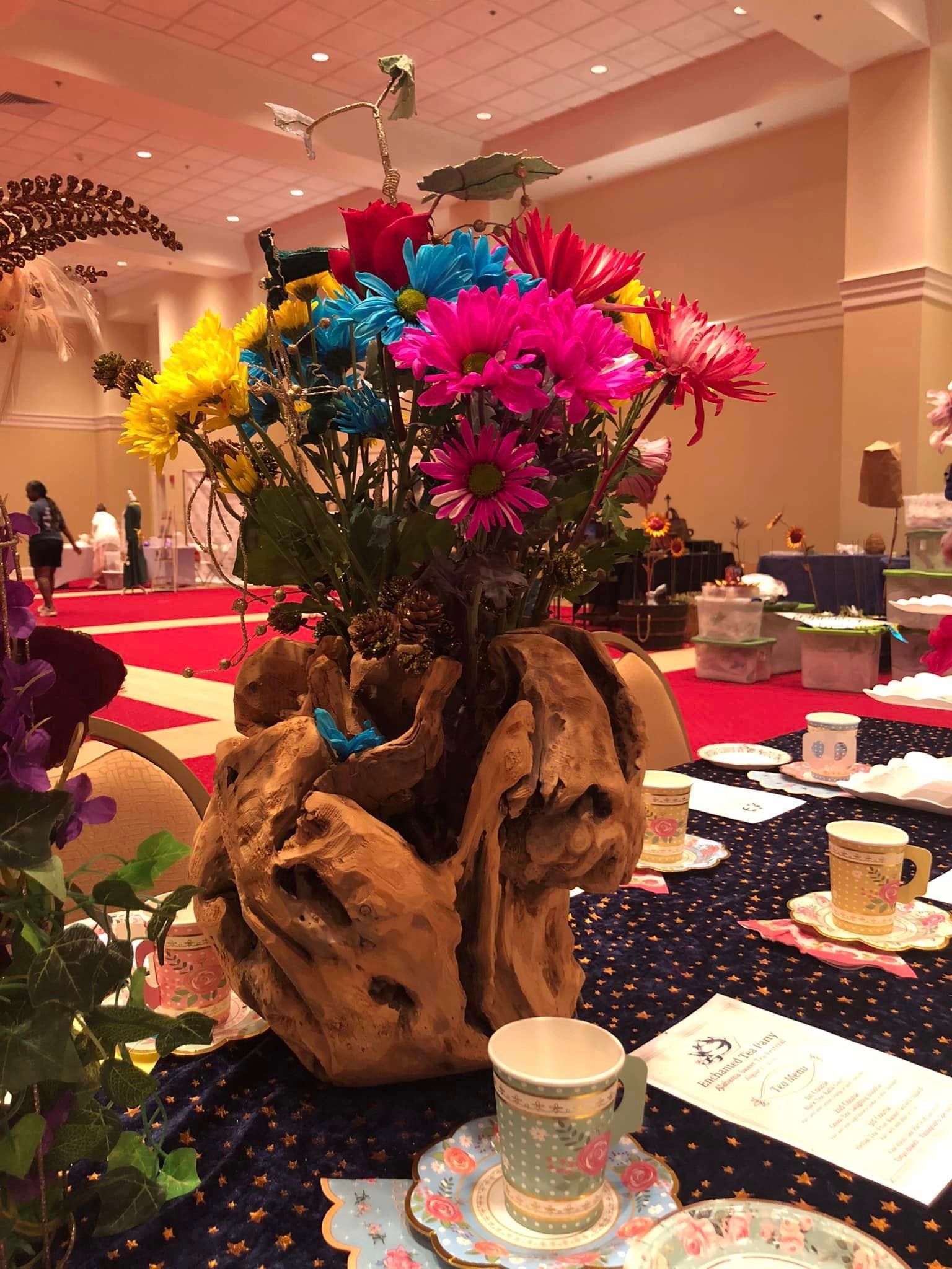 A vase of flowers is sitting on a table next to a cup and saucer.