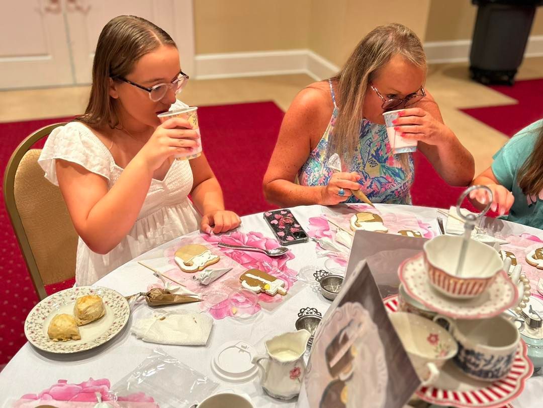 Two women are sitting at a table drinking tea.