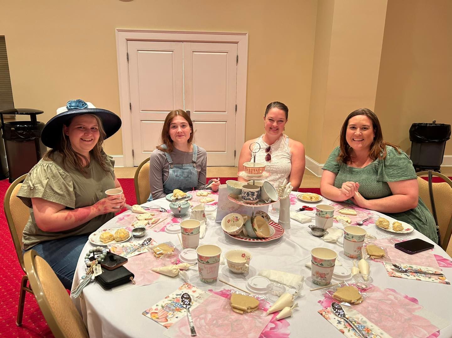 A group of women are sitting at a table with cups and saucers.