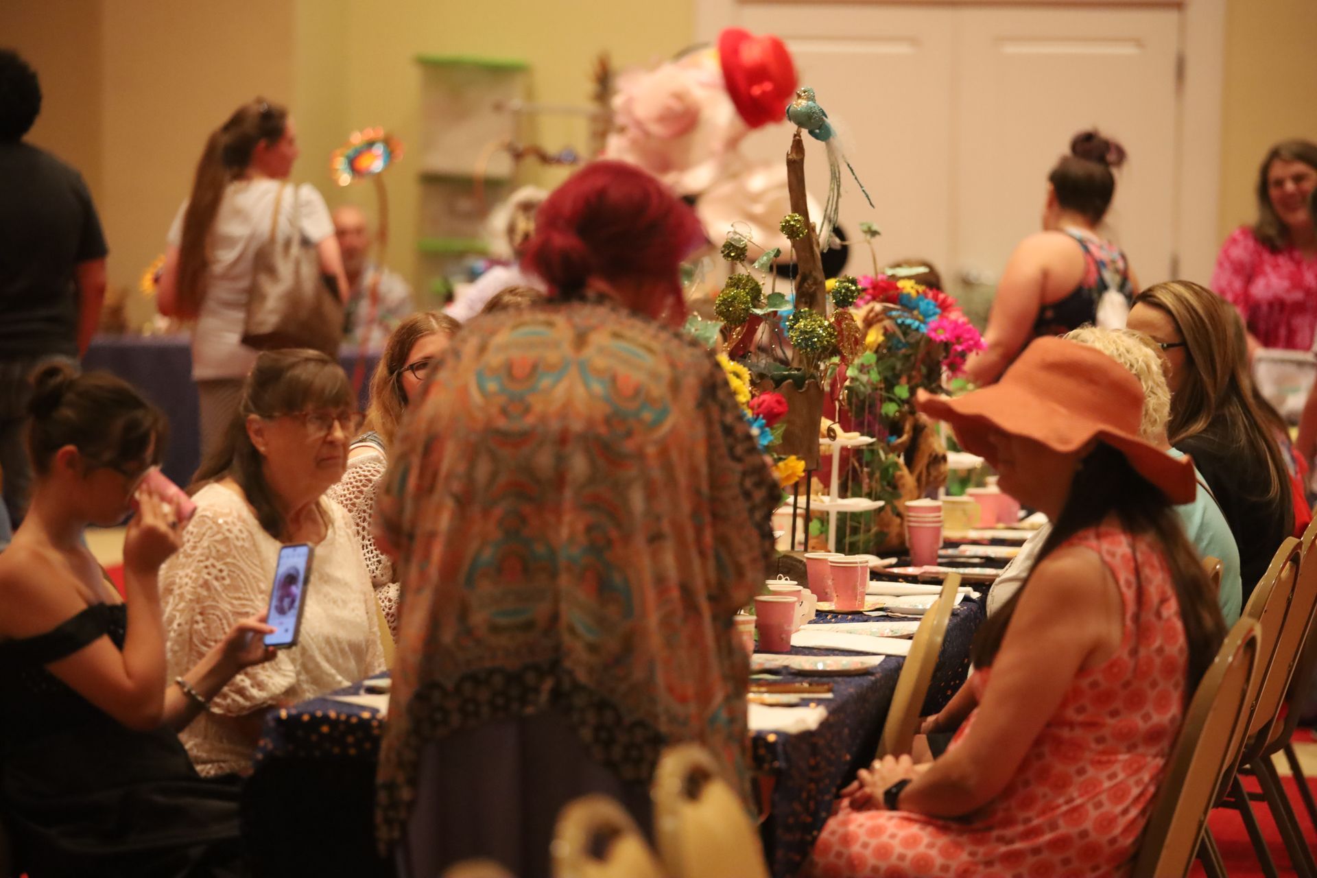 A group of people are sitting at a long table at a tea party.