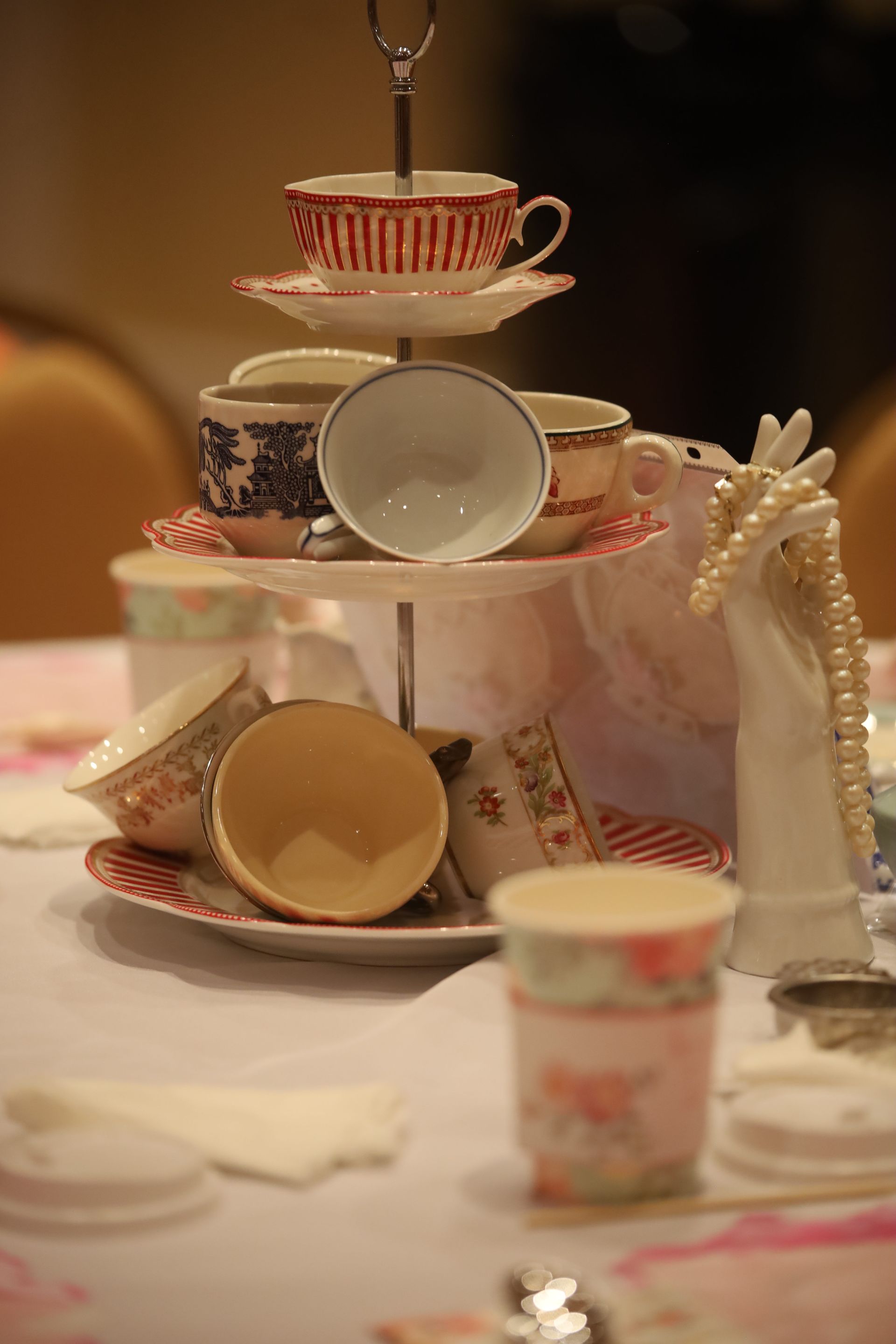 A stack of cups and saucers on a cake stand on a table.