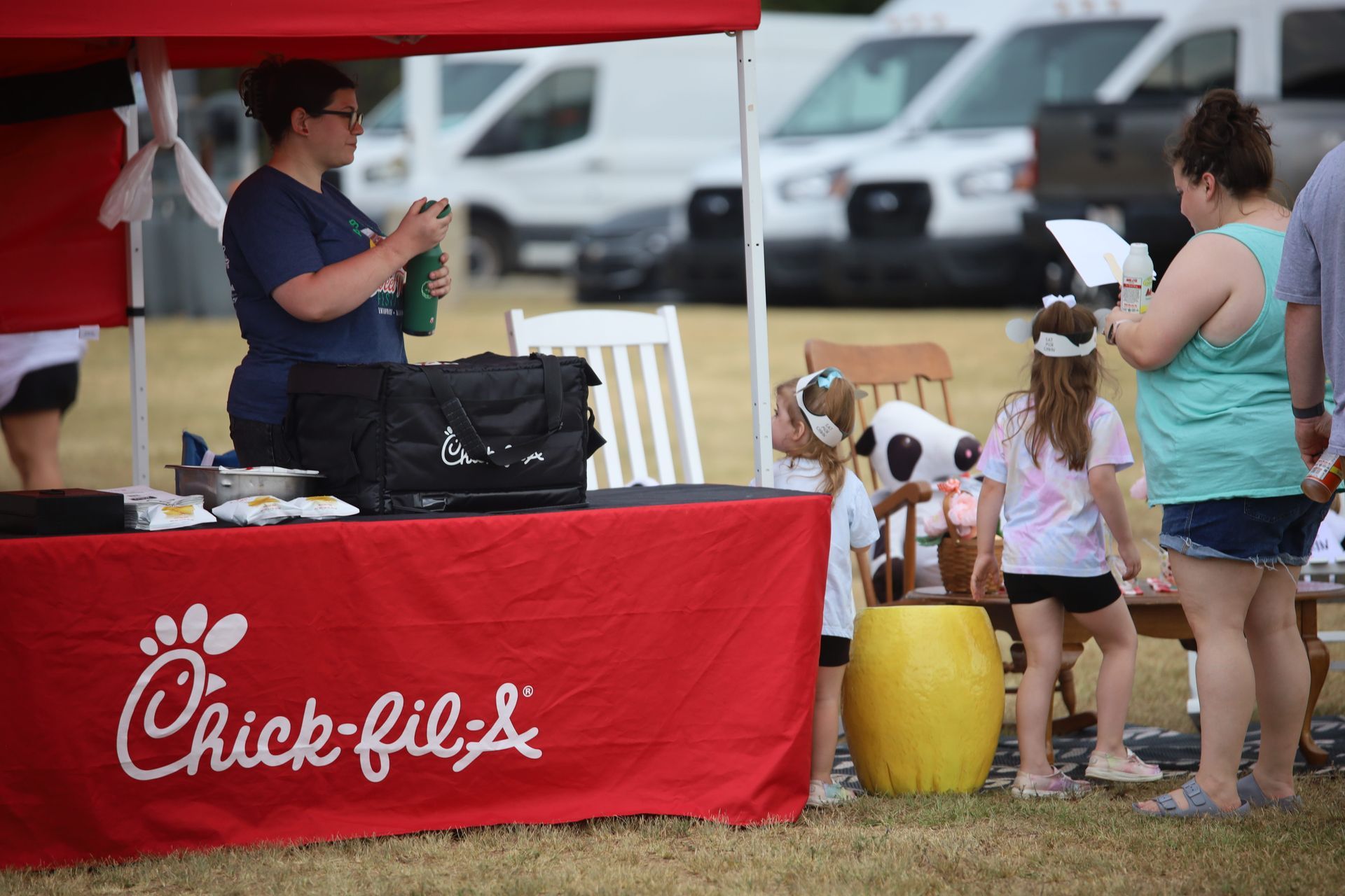 A group of people are standing around a chick-fil-a table.