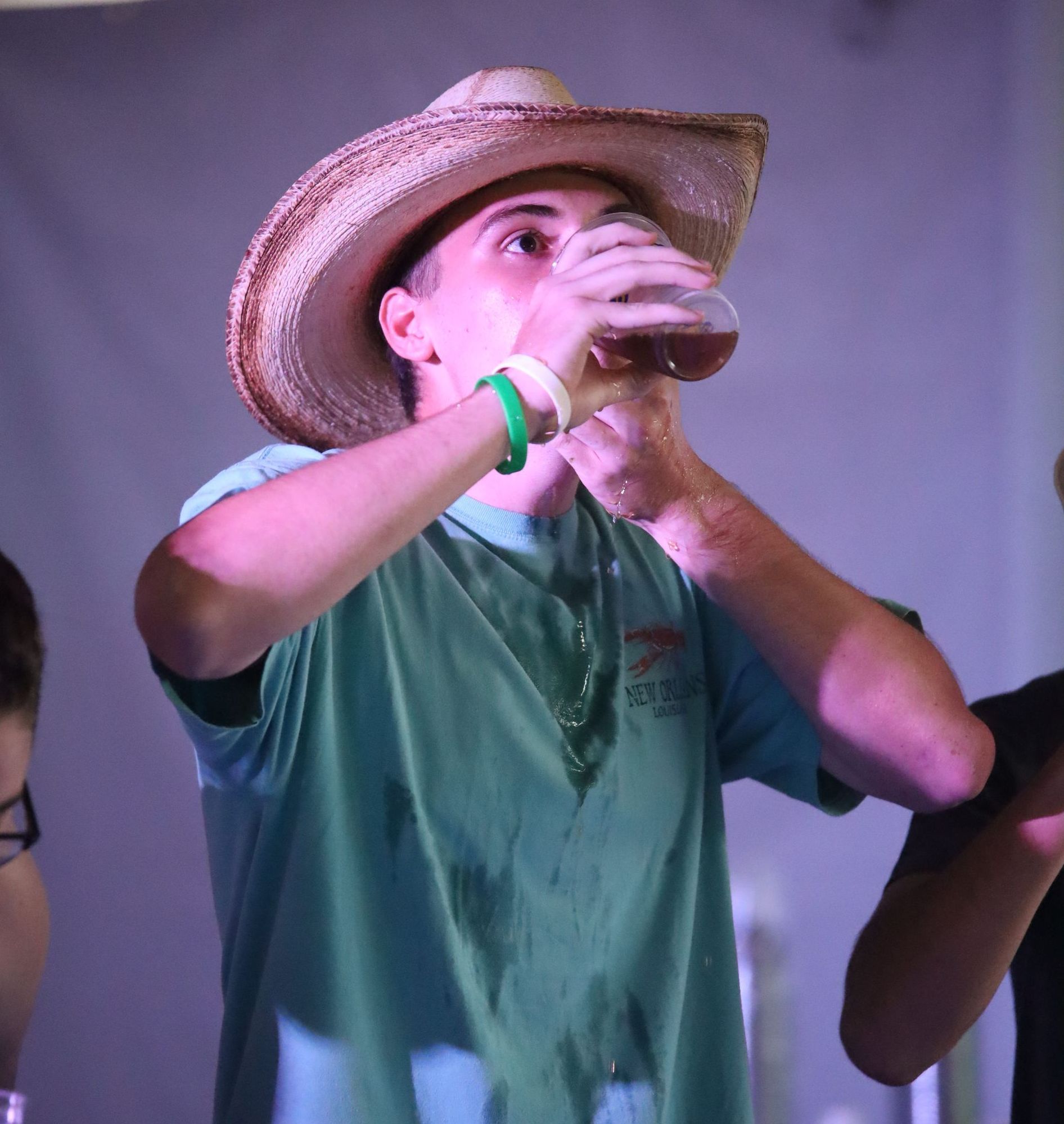 A man wearing a cowboy hat is drinking from a glass