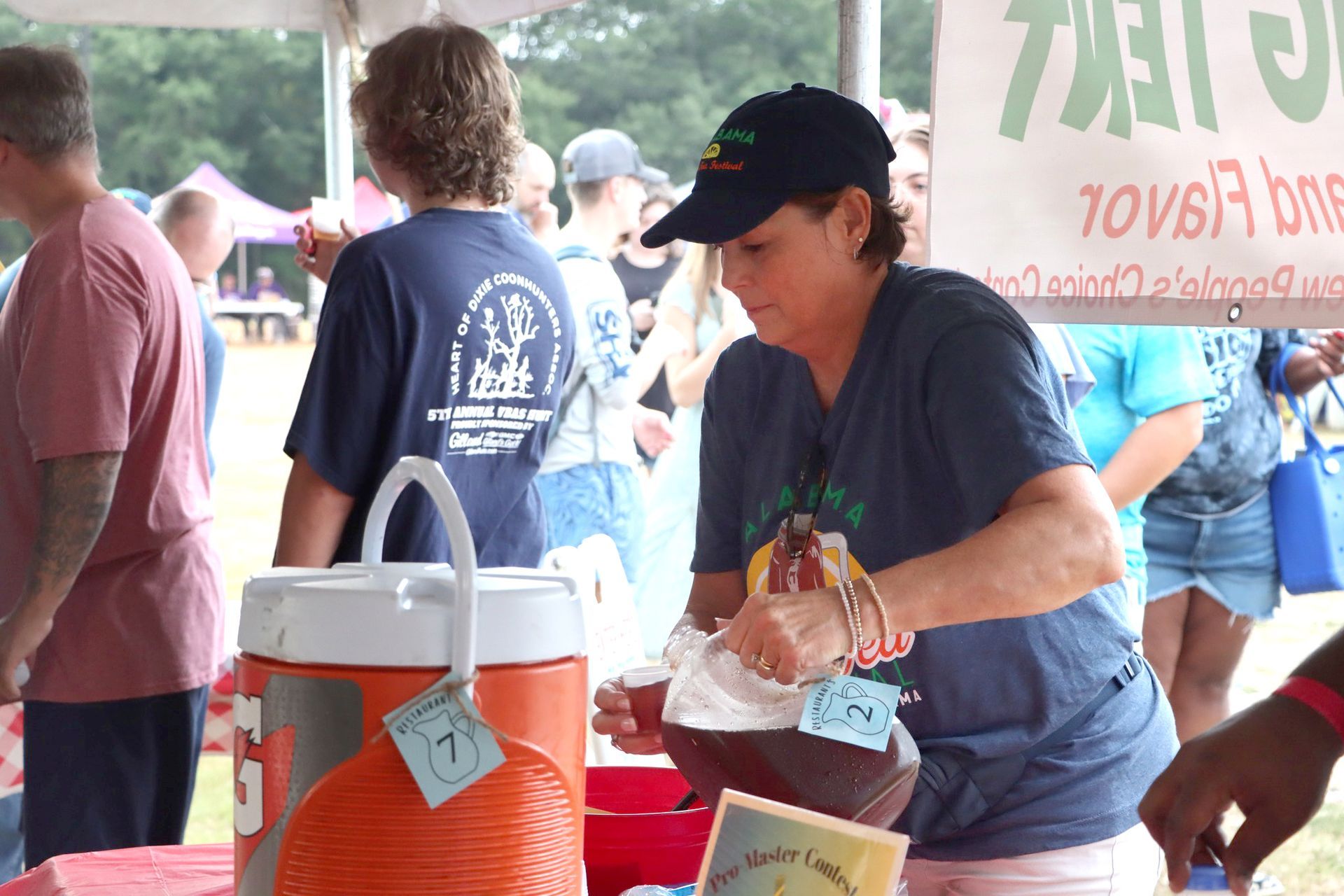 A woman in a blue shirt is pouring a drink from a cooler