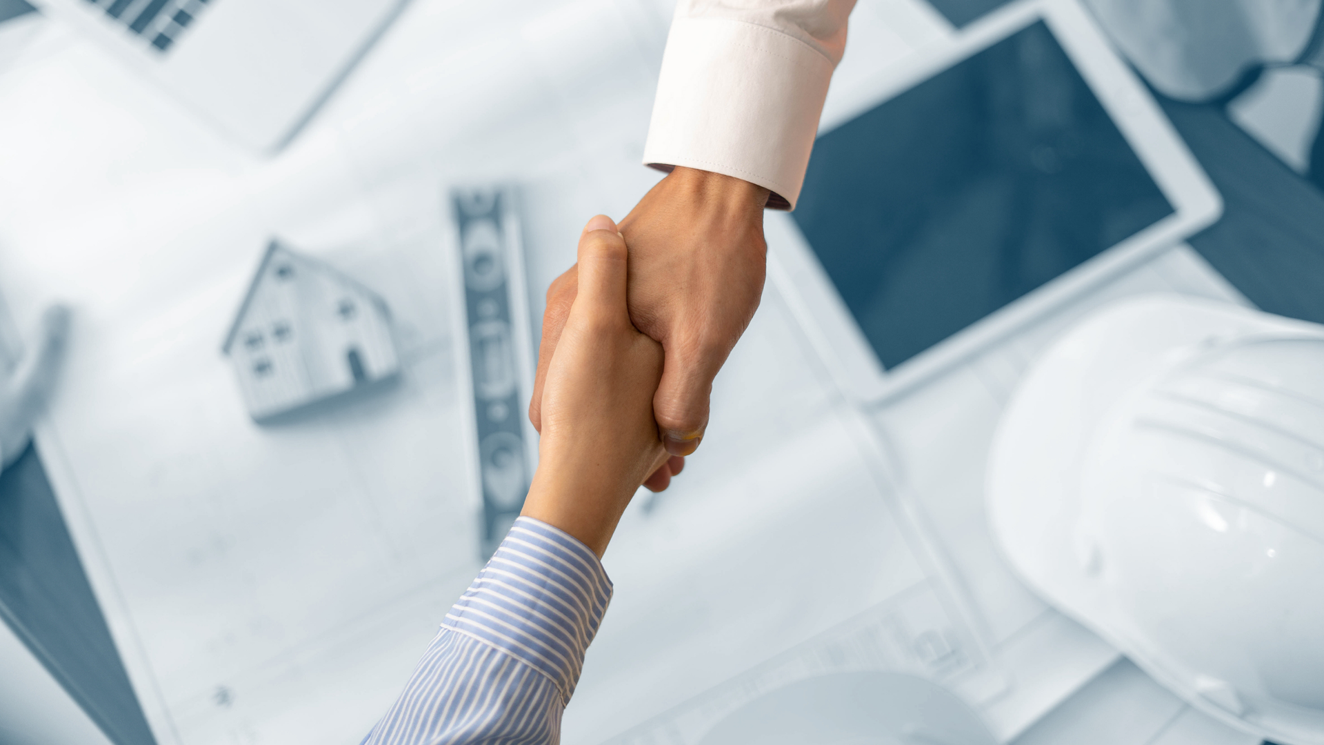 An architect and its client shaking hands over a .working table