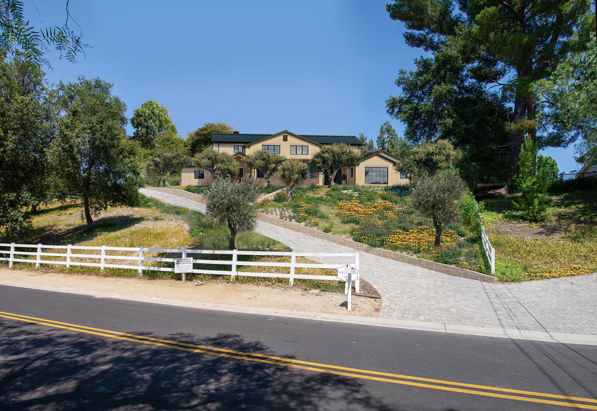 A large house sits on top of a hill next to a road