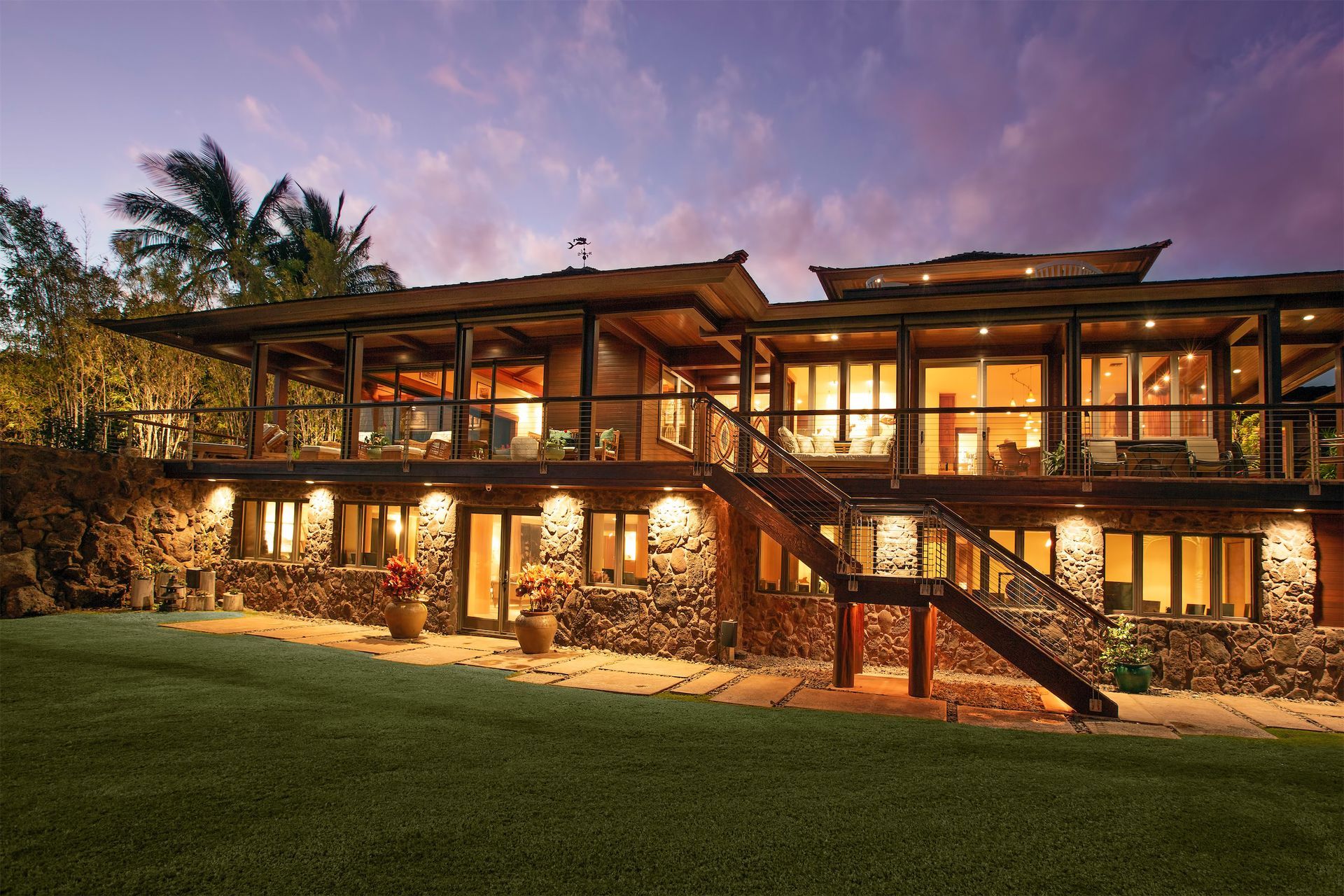 The Lanai Estate in Maui, HI lit up at dusk with purple and blue sky in the background.