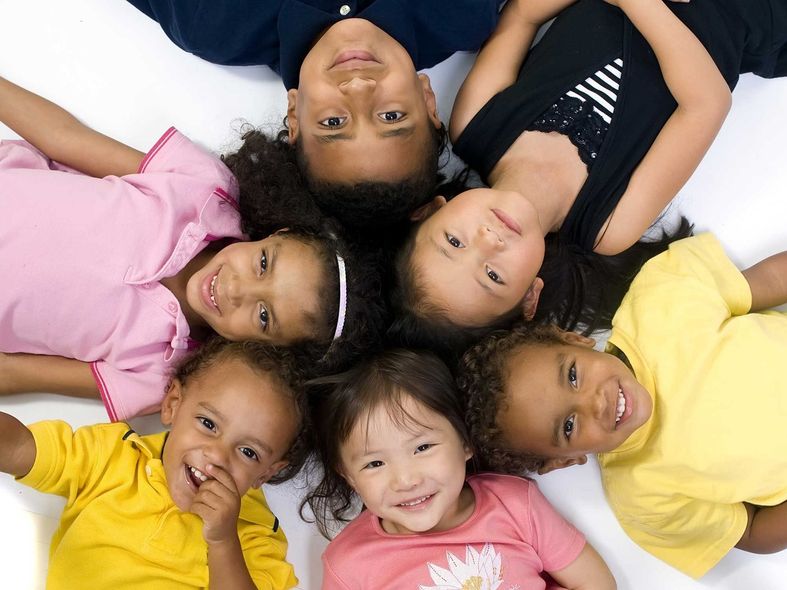 A girl in a wheelchair is sitting at a table with other children.
