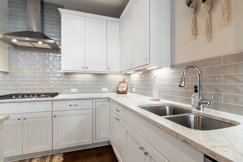 Bright modern white kitchen with quartz counters, subway tile backsplash, and stainless steel appliances