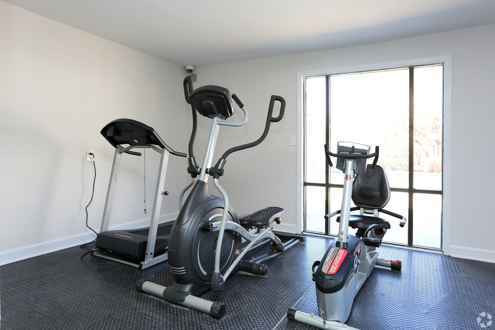 A gym with a treadmill , elliptical , and recumbent bike at Dwell @ 750