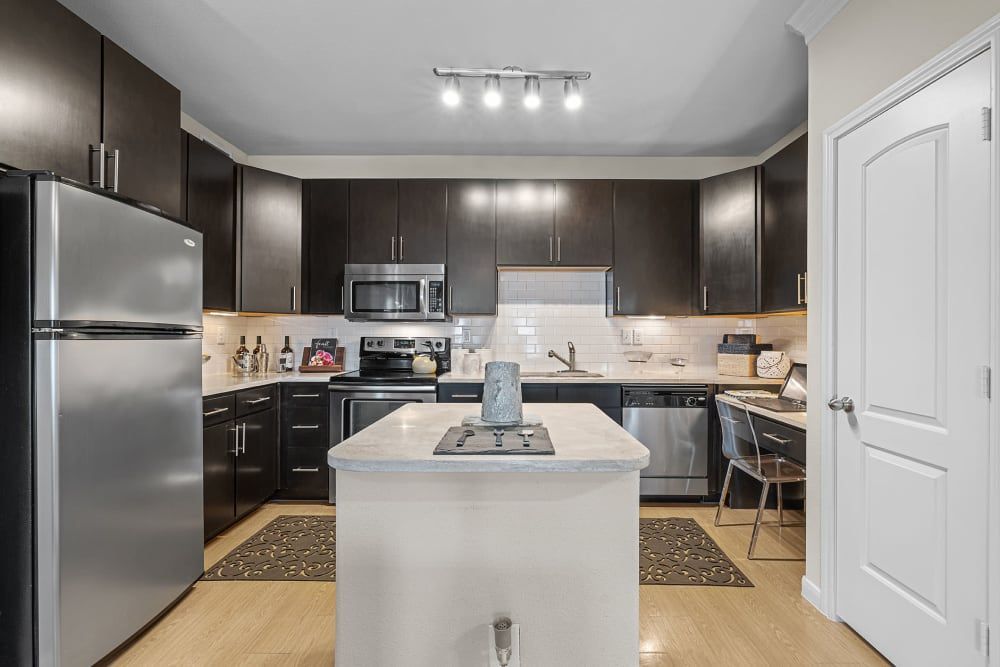 Community kitchen with stainless steel appliances and a large island in the middle at Marquis at the Reserve in Katy, TX.
