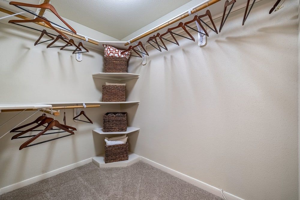 A walk-in closet with a lot of clothes hanging on the racks at Marquis at the Reserve in Katy, TX.