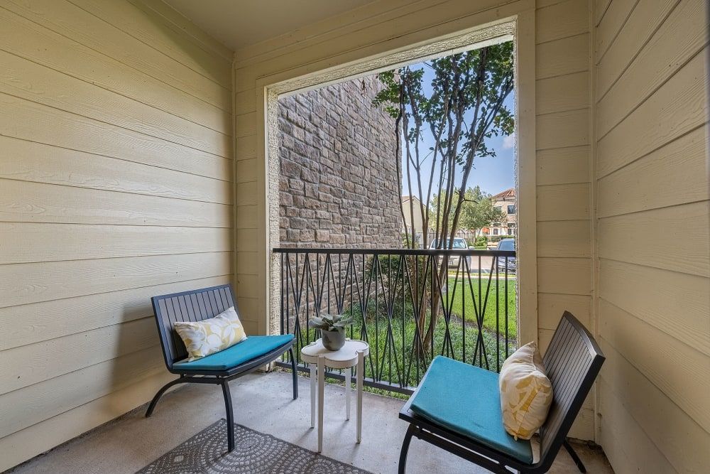 A balcony with a bench and chairs at Marquis at the Reserve in Katy, TX.