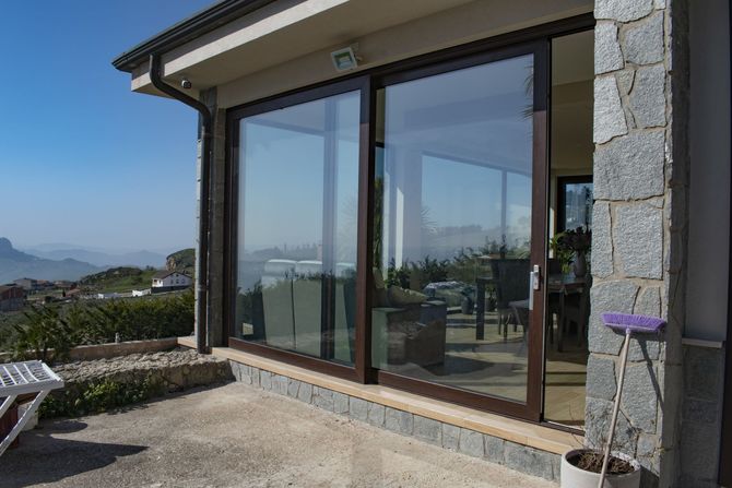 Una parete di finestre e porte scorrevoli in vetro con tende verticali in un luminoso e moderno spazio ufficio interno.
