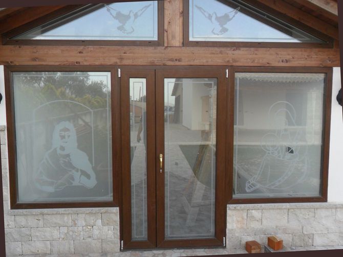 Un telaio di finestra in legno chiaro con pannelli di vetro poggiati su supporti metallici, che mostra un lato parzialmente aperto.
