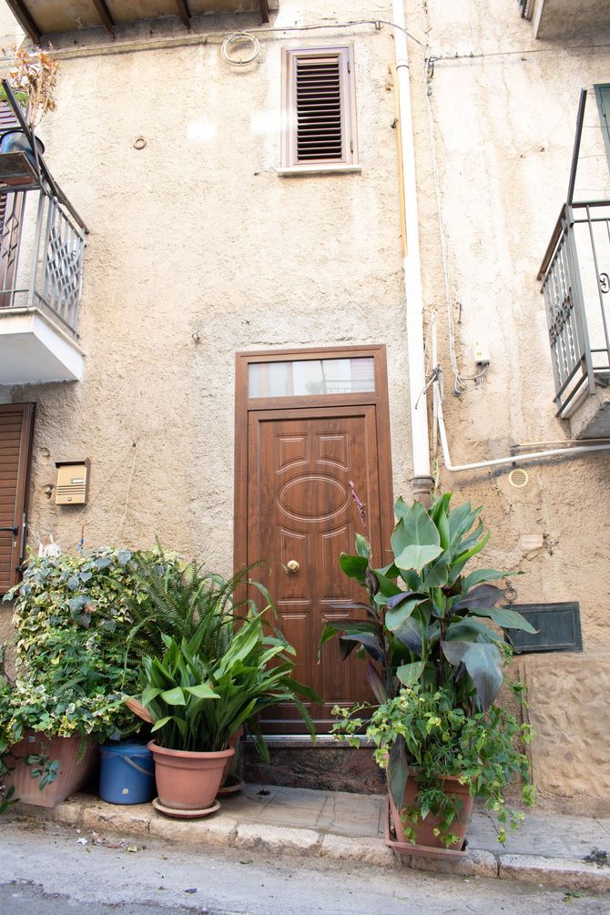Una porta d'ingresso con finitura effetto legno marrone, battente e maniglia dorati, accanto a una finestra verticale con vetro color ambra.