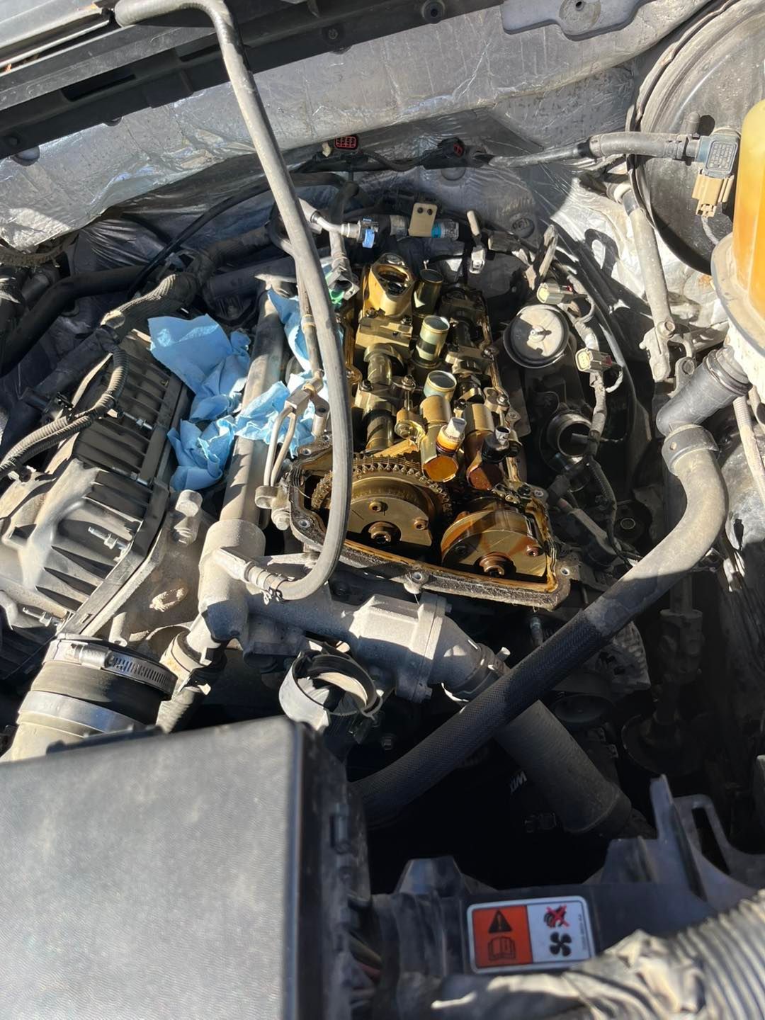 An overhead view of an open car engine bay with the valve cover removed, revealing internal mechanical components.