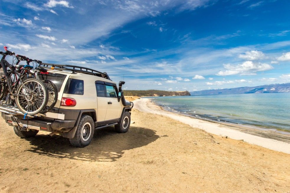 A White Suv With Two Bikes on the Back is Parked on a Beach — Northern Service Centre in Westcourt, QLD