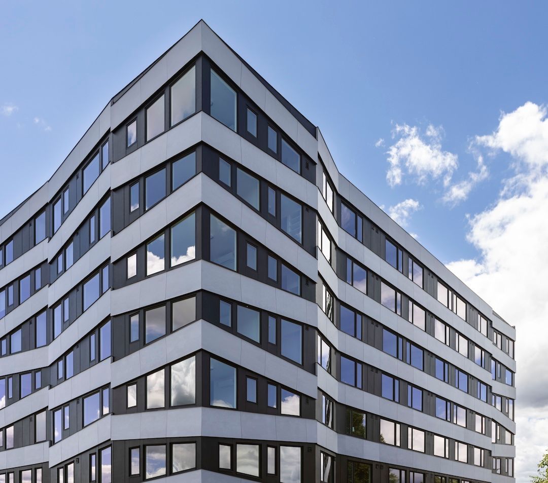 Modern gray-and-white office building with rows of windows against a blue sky