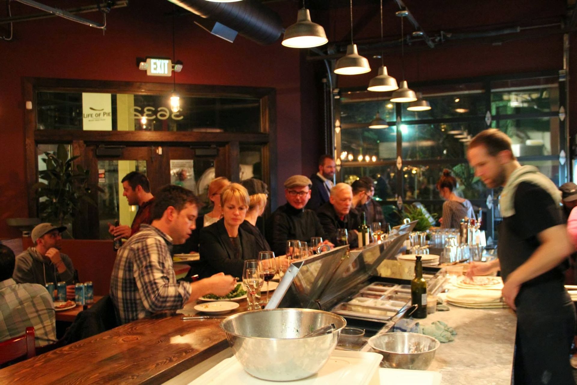 People seated at a bar in a restaurant, with a bartender working behind it.