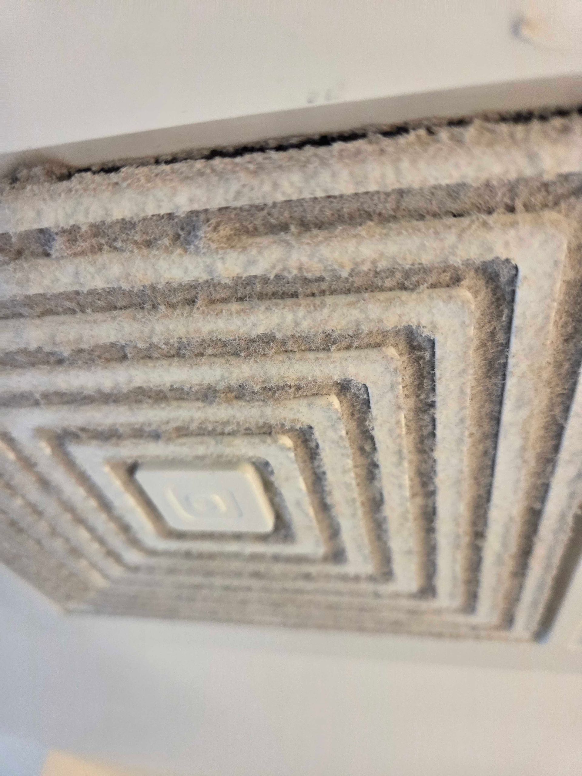 Square ceiling vent with concentric dusty gray trim around a central light fixture