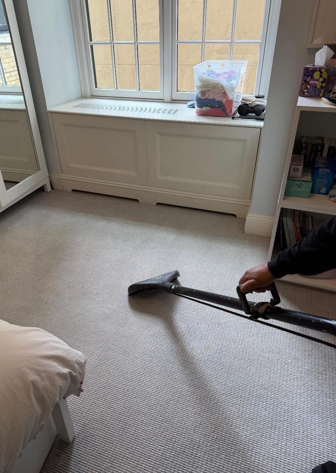 Blue vacuum cleaner on a white rug beneath a wooden bench in a living room.