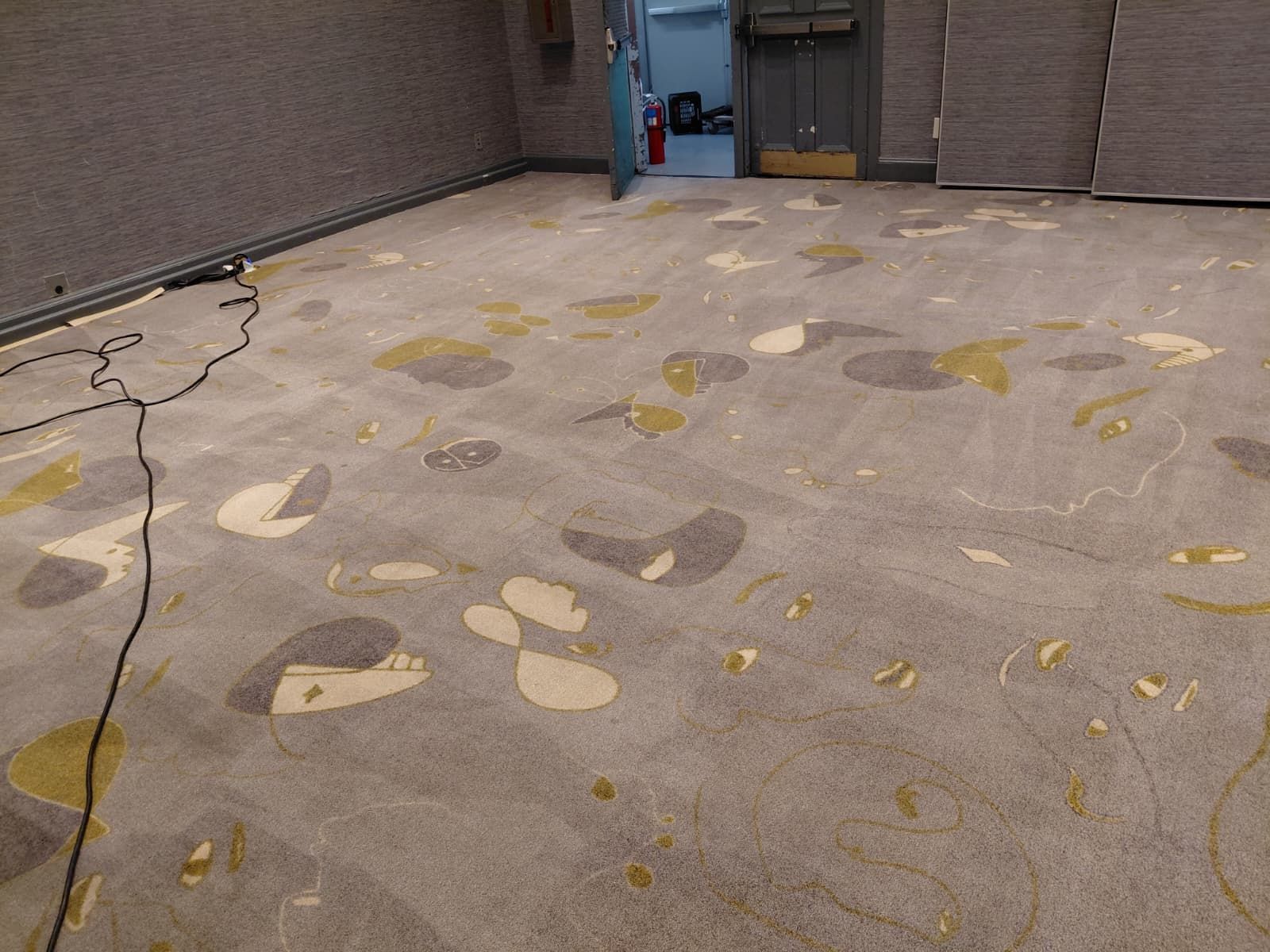 Cracked concrete patio with scattered patchy stains and a few doorways along the back wall