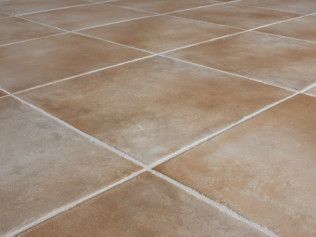 Tan ceramic floor tiles with white grout, laid in a diamond pattern.