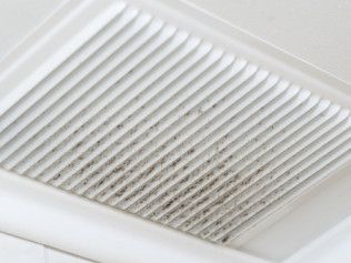 White ceiling vent with dark mold growth on the slats.
