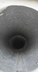 Inside of a gray cylindrical pipe, viewed looking down into the dark opening