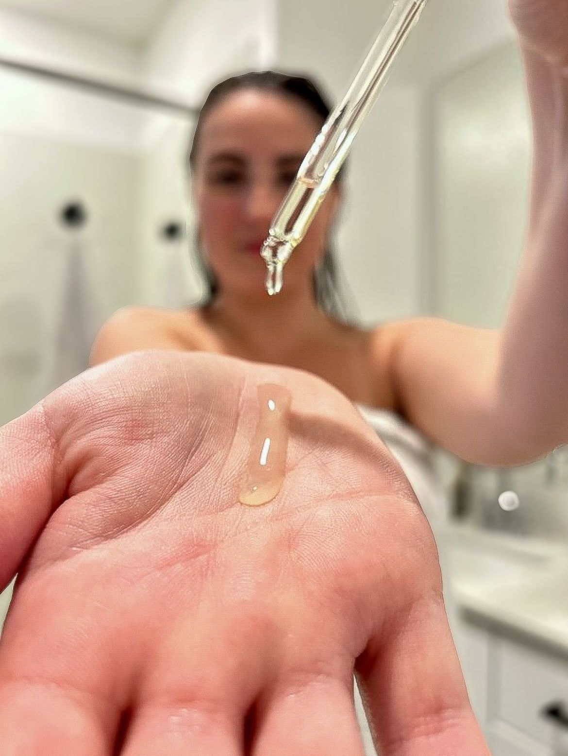 A woman is holding a dropper of liquid in her hand.