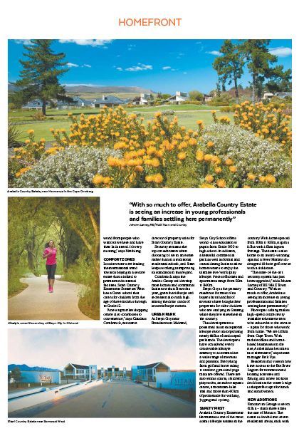 Magazine page with a wildflower field, a person on a path, and beach huts under a blue sky