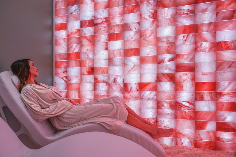 Person reclining on a lounge chair beside a glowing red-and-white illuminated wall
