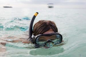 Snorkeler with mask and snorkel floating in calm ocean water