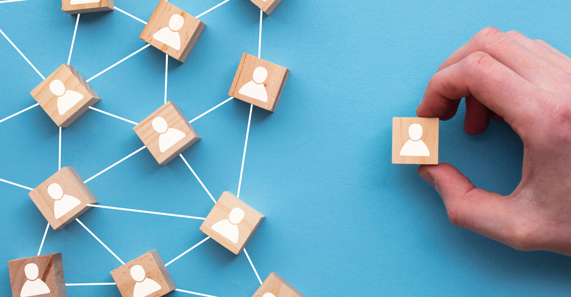 A hand holding a wooden block with a person icon, connecting with other blocks via lines, symbolizing networking.