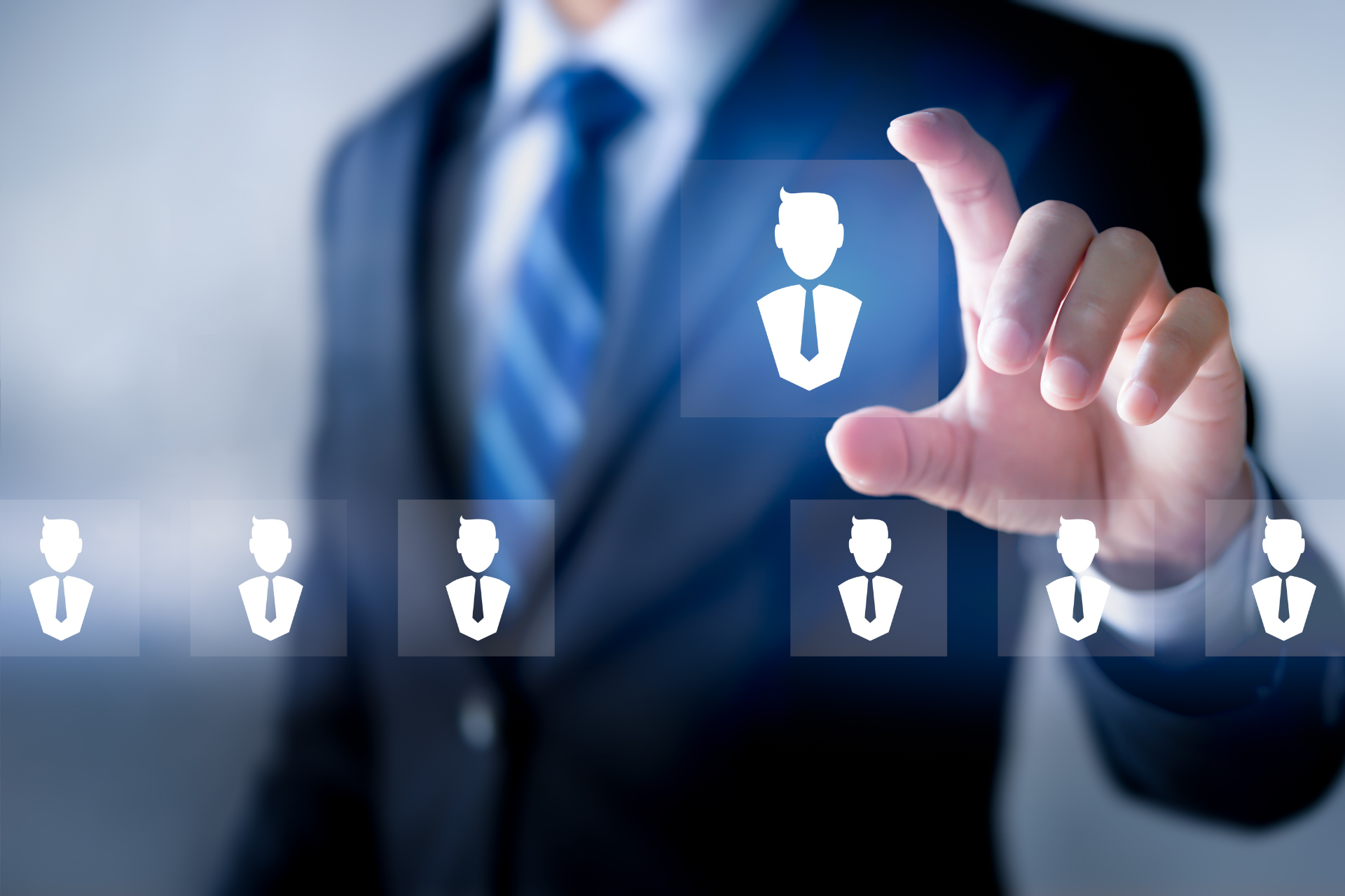 A person in a suit selects a glowing icon of a person from a digital interface, symbolizing recruitment or decision-making in a professional context.