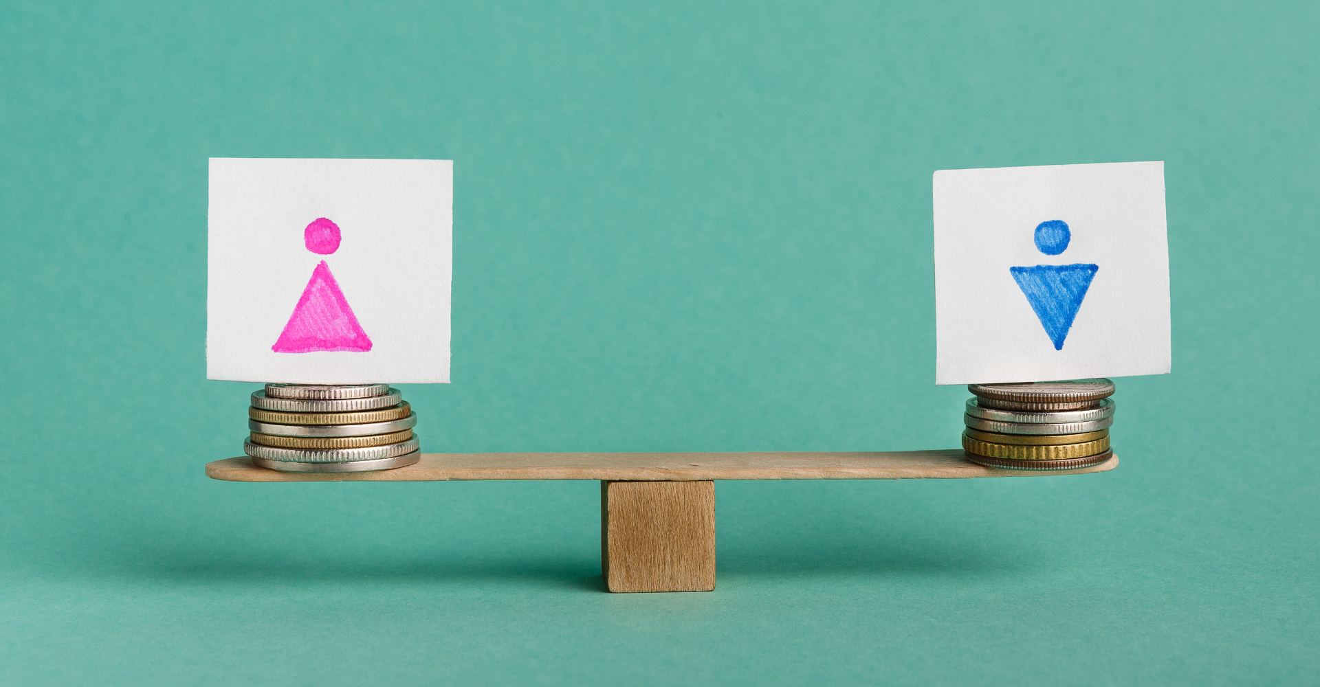 A balance scale with coin stacks on each side holds paper cutouts: pink female symbol on left, blue male symbol on right.