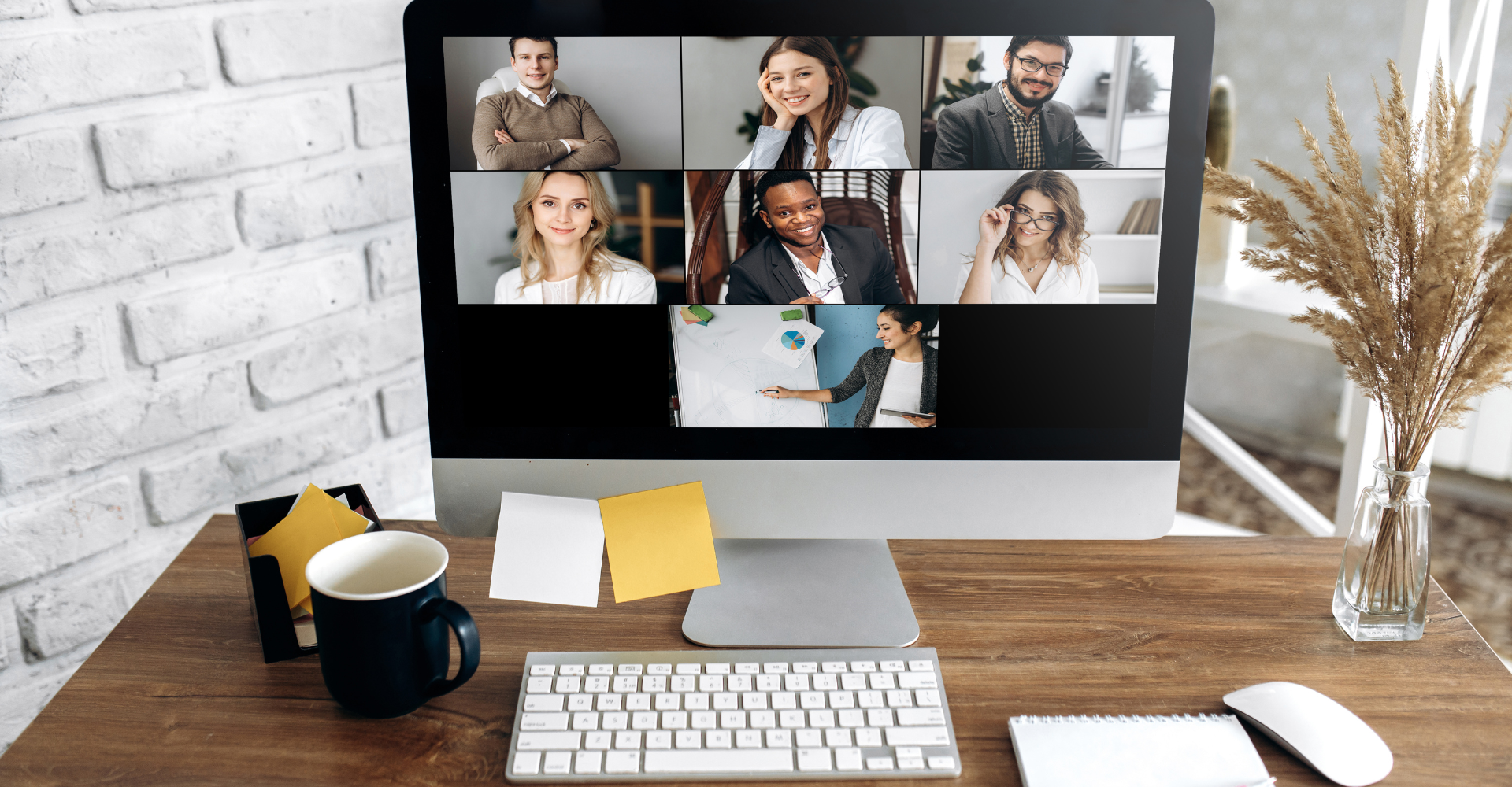 A computer screen displays a virtual meeting with six participants, smiling.