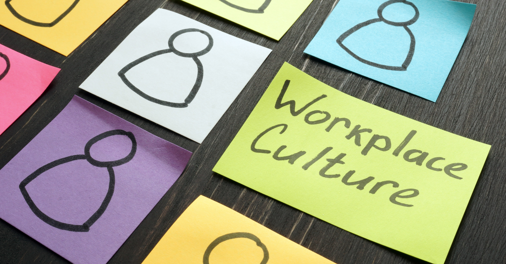 Sticky notes on a dark surface display simple human icons, with one featuring the words