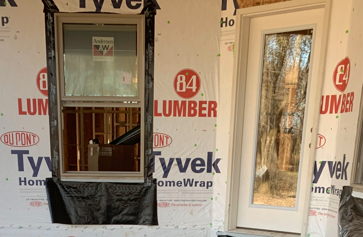A window and door is being installed in a house that is being built.