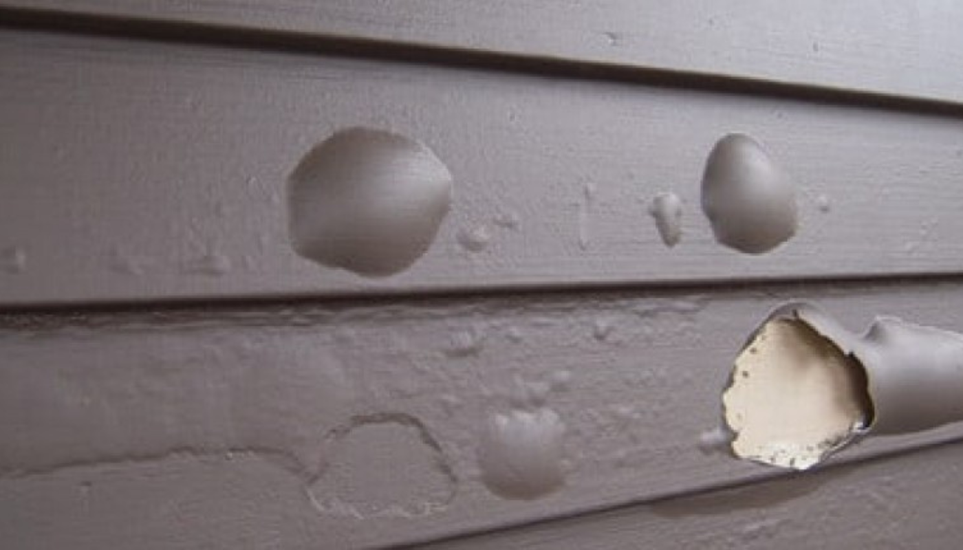 Brown painted siding with multiple blisters and peeling paint.