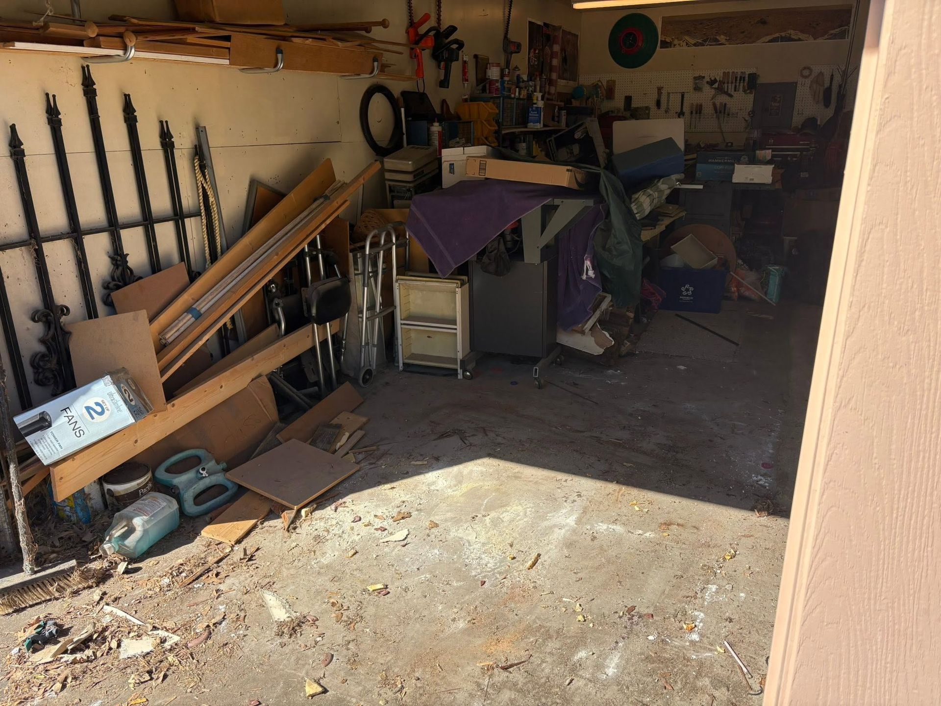 Cluttered garage with tools, boards, and equipment piled along the walls and floor.