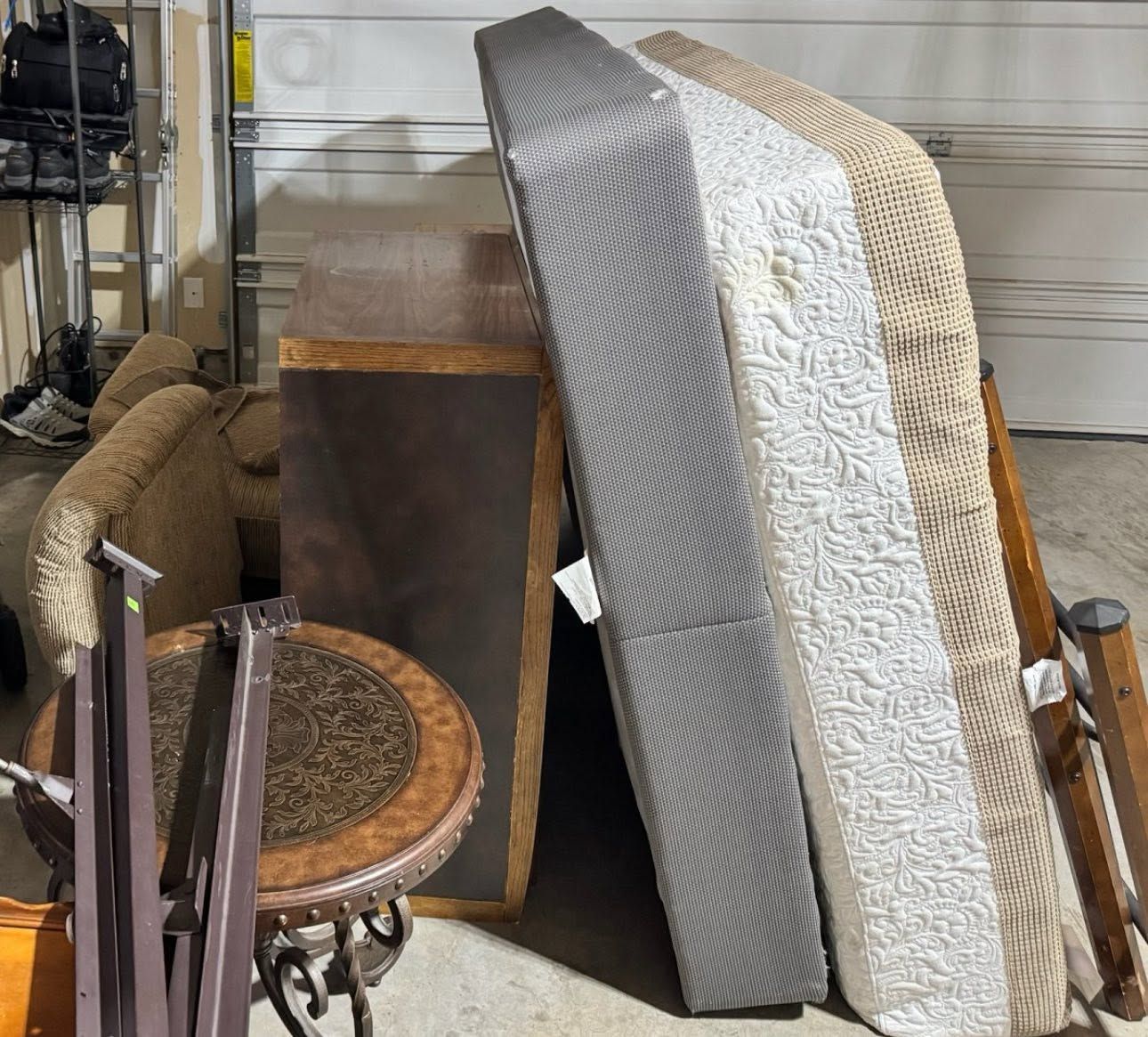 Stacked rugs and furniture in a cluttered garage or storage area