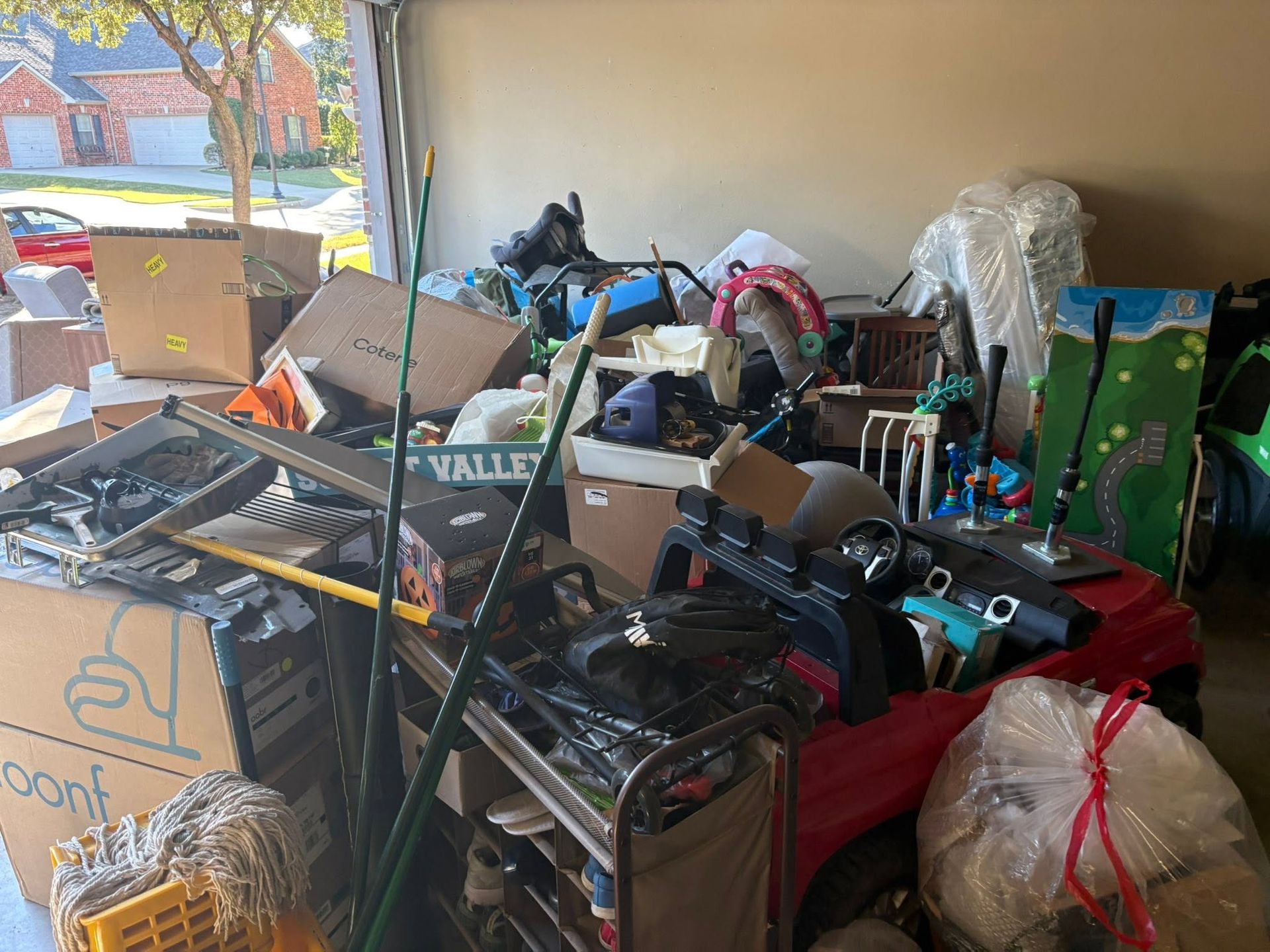 Cluttered room filled with boxes, bags, tools, and assorted household items piled on shelves and the floor