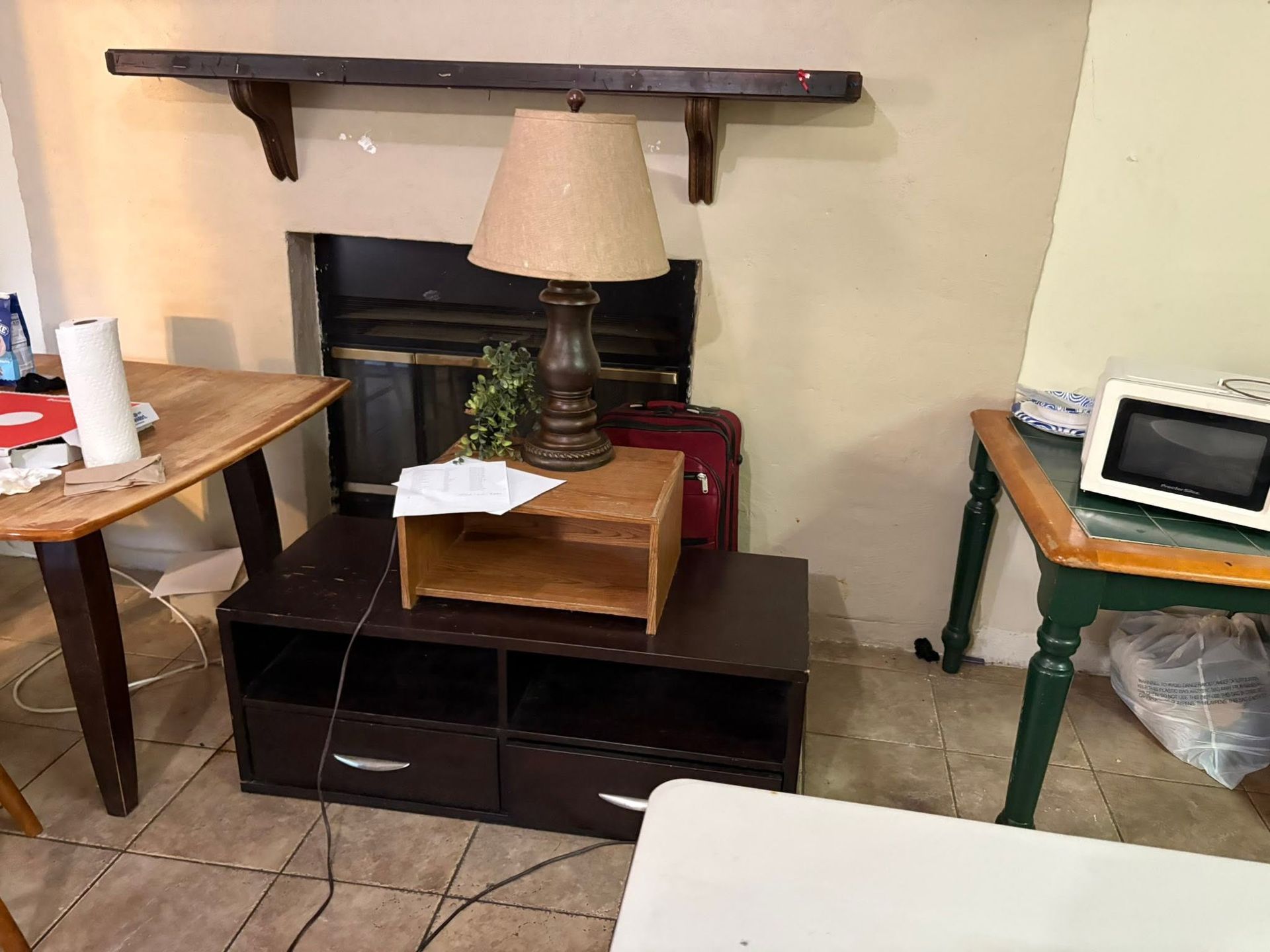 Living room with a fireplace, lamp on a stand, and small tables on either side.