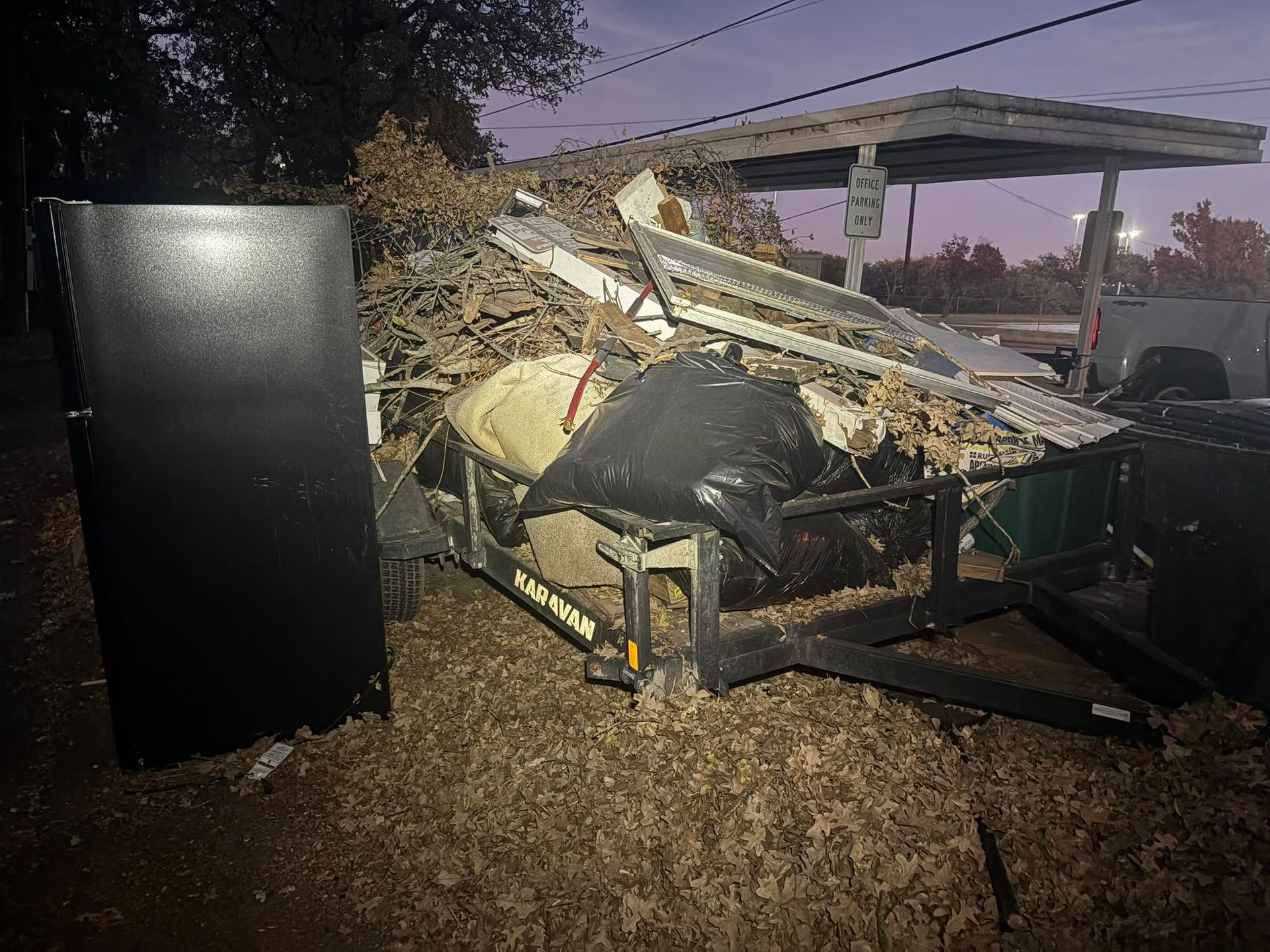Overturned outdoor furniture and debris in a yard beside a black cabinet at dusk.