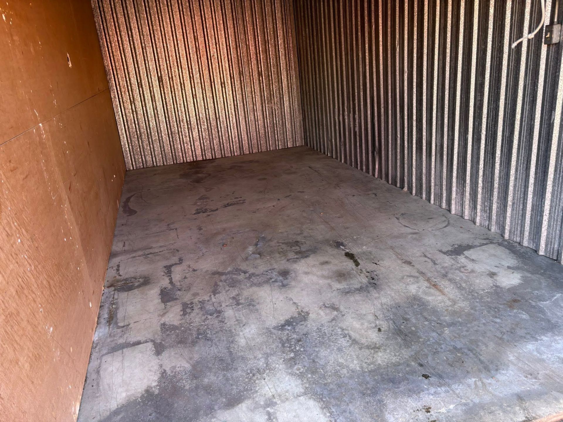 Empty storage container with a dirty concrete floor and corrugated metal walls
