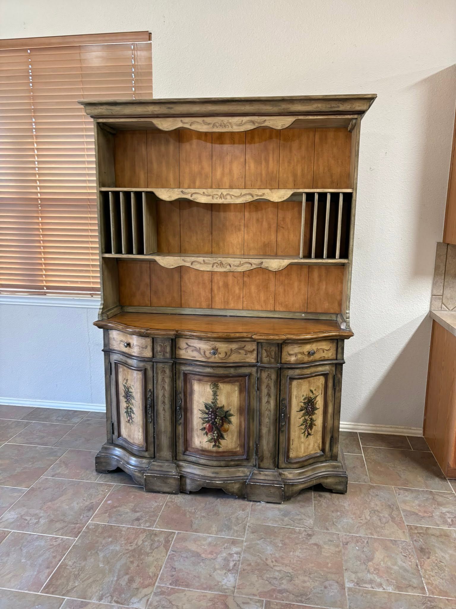 Old wooden hutch with shelves and decorative lower cabinets in a room with tile floor.